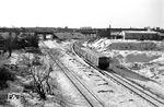 Blick von der Wiesendammbrücke, Blickrichtung Westen, auf einen ET 165, der aus Spandau-West kommt und über Siemensstadt-Fürstenbrunn nach Gesundbrunnen fährt. Das linke Gleis gehört zur Lehrter Bahn und unterquert die Fernbahn von Spandau zur Stadtbahn. Der Turm im Hintergrund ist das Spandauer Rathaus. Die hochliegende Fachwerkbrücke führt vom Güterbahnhof Ruhleben zum Anschluss des Kraftwerks Reuter. (12.1964) <i>Foto: Jürgen Hagemann</i>
