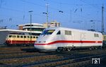 Im Bahnhof Opladen trifft Triebkopf 401 059 am Dummyzug Dsts 83770 auf die vorbeifahrende 114 501. Im Hintergrund ist das Sp Dr L60-Stellwerk "Of" zu sehen, das am 28.07.2012 außer Betrieb ging und im Zuge des Bahnhofsumbaus im Mai 2015 abgerissen wurde. (28.03.1991) <i>Foto: Joachim Bügel</i>