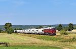 V 200 507 mit dem Ganzzug aus dem Karsdorfer Zementwerk bei Kleinjena kurz vor Naumburg (Saale). Links der großen Bäume ist das Empfangsgebäude des ehemaligen Bahnhofs zu sehen, der gegenwärtig als Haltepunkt im Stundentakt von der RB 77 (Naumburg Ost – Wangen) bedient wird. (03.08.2026) <i>Foto: Ralf Opalka</i>