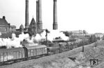 52 7550 vom Bw Berlin-Grunewald auf dem Gleis zum Berlin Lehrter Gbf am Kraftwerk Moabit in Höhe des S-Bahnhofs Putlitzstraße, in dem sich gerade Ringbahn-Züge begegnen. Hinter der 52er sind zwei Besonderheiten eingereiht: Der erste Wagen ist einer der beiden 1934 umgebauten Gl "Dresden" zum "langen Oppeln". Der zweite Wagen ist ein DR-Neubau aus den frühen 1950er Jahren. Das im Oktober 1900 in Betrieb gegangene Heizkraftwerk Moabit dient der Versorgung von ca. 44.000 Haushalten in den umliegenden Stadtteilen mit Fernwärme und Strom. Das Kraftwerk wurde bislang primär mit Steinkohle befeuert und befindet sich 2026 in der Umstellung auf Biomasse und Erdgas. (04.1959) <i>Foto: Jürgen Hagemann</i>