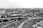 Panoramablick vom Humboldthain auf den Bahnhof Berlin Gesundbrunnen. Vor dem Bahnhof verläuft von links die Badstraße, von rechts kommt die Brunnenstraße. Genau am Bahnhofszugang treffen sie aufeinander. Im Hintergrund ist die Swinemünder Brücke zu sehen, von den Berliner auch spöttisch "Millionenbrücke" genannt, da sie zu ihrer Bauzeit zwischen 1902 und 1905 die teuerste und größte Brücke Berlins war, und nach heutiger Währung rund 8 Millionen Euro kostete. Dahinter stehen die Häuser des Bezirks Pankow. Ein S-Bahnzug der Ringbahn verlässt gerade den Bahnhof. (04.1959) <i>Foto: Jürgen Hagemann</i>