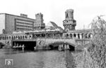 Über die Sektorengrenze an der Oberbaumbrücke fährt ein U-Bahn-Zug mit einem Triebwagen der Bauart AIT mit Stahlwagenkasten (18. Lieferung, Baujahr 1928), einem Triebwagen AIT (13. Lieferung, Baujahr 1913), einem Beiwagen AIB (8. Lieferung, Baujahr 1908) und einem Triebwagen AIT (13. Lieferung, Baujahr 1913). Im April 1960, als dieses Foto entstand, verband die Brücke noch die Bezirke Friedrichshain und Kreuzberg über die Spree. Die U-Bahnlinie B fuhr von der Station Warschauer Brücke nach Ruhleben im Bezirk Spandau. Mit dem Bau der Berliner Mauer am 13. August 1961 wurde die Oberbaumbrücke für den gesamten Verkehr einschließlich der U-Bahn gesperrt. Zu einer Daueröffnung für Fußgänger kam es ab 1972 durch das Viermächteabkommen über Berlin. Seit 1995 wird die Brücke wieder für die U-Bahn und für den Straßenverkehr genutzt. Die am 23. April 1945 von den Deutschen zerstörten Brückentürme wurden erst nach der deutschen Wiedervereinigung wieder instand gesetzt. (04.1960) <i>Foto: Jürgen Hagemann</i>