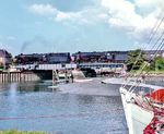 012 061 und 012 100 fahren mit D 437 über die Klappbrücke am Husumer Hafen, die 1979 durch eine Waagebalkenbrücke ersetzt wurde. Links steht das Stellwerk "Husum Brücke Br", das die Bedienung der Brücke abhängig von den Stellwerken Husum "Hf" und Husum Nord "Hn" regelte und mit dem Neubau der Brücke auch verschwand. (08.1970) <i>Foto: Ulrich Hesse</i>