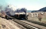 44 463 (Bw Rottweil) mit einem Durchgangsgüterzug auf dem Tuttlinger Gleis südlich von Rottweil. Im Hintergrund ist der Primtalviadukt der Strecke Rottweil—Balingen (Württ) zu sehen. Der Viadukt bestand ursprünglich aus 7 Bögen. Sechs davon sind erhalten geblieben, der 7. Bogen über die Strecken nach Villingen (Schwarzw) und Tuttlingen musste bei der Elektrifizierung weichen. Die Strecke nach Balingen (Württ) war bereits 1971 bis Schömberg (b Balingen) stillgelegt worden.  (03.1965) <i>Foto: Rolf Hahmann</i>