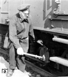 Ein altgedienter Wagenmeister kontrolliert - vermutlich im Rahmen der Bremsprobe - das Fahrwerk eines badischen Gepäckwagens der Bauart Pw4ü Bad06 in Berlin Anhalter Bahnhof. (1934) <i>Foto: RVM</i>
