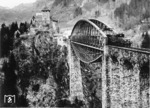 1883/84 wurde die ursprüngliche Brücke auf der Arlbergbahn nach einer Bauzeit von nur einem Jahr als größte Spannbogenbrücke Österreichs fertiggestellt. Steigende Achslasten führten dazu, dass die Trisannabrücke 1923 mit einem unten angeordneten sogenannten Fischbauchträger (Foto) verstärkt werden musste. 1964 wurde das Stahltragwerk durch eine Neukonstruktion ersetzt (vgl. Bild-Nr. 13292). Die verstärkte Brücke wird gerade von einer der typischen Arlbergloks der Reihe 1089/1189 überquert. (1938) <i>Foto: RVM</i>
