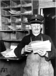 Ein Packmeister im Gepäckwagen beim Sortieren von Gepäckscheinen und Begleitpapieren der Expressgutsendungen. (1940) <i>Foto: RVM</i>