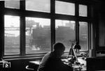 Blick durch die rußgeschwärzten Fenster der Lokleitung des Bw Altona auf 74 705, die gerade eine der beiden Doppeldrehscheiben befährt. Im Hintergund ist der Portaldrehkran der Großbekohlungsanlage zu erkennen. (11.02.1957) <i>Foto: Walter Hollnagel</i>