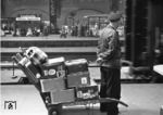 Ein Gepäckträger mit internationalem Gepäck aus Rom und Paris in Hamburg Hbf. (02.07.1956) <i>Foto: Walter Hollnagel</i>