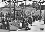 Auch zwei Jahre nach den Kämpfen um die Festungsstadt Sewastopol zeigen sich am Bahnhof noch deutliche Spuren der schwer umkämpften Stadt. Deutsche Soldaten warten auf den Zug, die einzige (russische) Zivilistin ist von dem Fotografen eher peinlich berührt. (1943) <i>Foto: Walter Hollnagel</i>