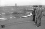 Blick vom Dach des Wasserturms des Bw Hamburg-Altona auf den 54-ständigen Ringlokschuppen mit den beiden 23m Drehscheiben. Im Hintergrund sind die Schornsteine des Kraftwerks für die Wechselstromerzeugung der Hamburger S-Bahn zu erkennen. Der Grund für die Anwesenheit der "wichtigen" Herren auf dem Dach ist allerdings unbekannt. (06.06.1958) <i>Foto: Walter Hollnagel</i>