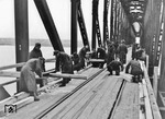 Bei der Instandsetzung von Eisenbahnbrücken wurde das Gleis nicht selten mit Holzbohlen versehen, um auch Kraftfahrzeugen die Überfahrt zu ermöglichen. (1943) <i>Foto: Walter Hollnagel</i>