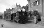 Lok 9 "Plettenberg" fährt mit einem Personenzug durch die Plettenberger Bahnhofstraße in Richtung Stadtmitte am früheren Stammwerk der Fa. Schade vorbei. (26.07.1953) <i>Foto: H.J. Sievers</i>