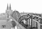 1952 wurde der über der mittleren Stromöffnung eingesetzte behelfsmäßige SKR-Stahlüberbau (Schaper-Krupp-Reichsbahn) wieder durch einen Bogen ersetzt, was der Brücke ihr ursprüngliches Aussehen wiedergab. Aus einem der alten Brückentürme entstand dieses Bild einer pr. T 18, die die Hohenzollernbrücke Richtung Deutz überquert. (1952) <i>Foto: Fischer</i>