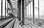 Die Mönchengladbacher 23 039 auf der Hohenzollernbrücke in Köln. Im Hintergrund sind die Halle des Hauptbahnhofs und das Direktionsgebäude am Rheinufer auszumachen. (04.1960) <i>Foto: Fischer</i>