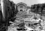 Blick auf die Trümmer des ehemaligen Querbahnsteigs des Leipziger Hauptbahnhofs. Der Angriff der 8. US-Luftflotte am 7. Juli 1944 verursachte schwerste Beschädigungen vor allem an der Westhalle und der Querbahnsteighalle. 46,2 Tonnen Bomben trafen an diesem Tag den Bahnhof, wobei zunächst einer der stützenden Abschlussbögen aus Stahlbeton brach. Dadurch kam es in den folgenden 20 Minuten zu einer Kettenreaktion, bei der die Stahlbetonbögen zwischen den Hallenschiffen und das Dach der Querbahnsteighalle komplett einstürzten. Die Osthalle blieb weitgehend unversehrt. An diesem Tag starben in den Luftschutzkellern zwischen den Bahnsteigen hunderte Eisenbahner und Reisende. Unmittelbar vor dem Hauptbahnhof und in der klaffenden Lücke des zerstörten Querbahnsteigs auf der Ebene der einstigen Gepäckanlagen mussten innerhalb von sechs Jahren rund 20.000 Sprengungen ausgeführt und 30.000 Kubikmeter Schutt beseitigt werden. Die Sprengungen waren nötig, um die Stahlbetontrümmer so weit zu verkleinern, dass sie abtransportiert werden konnten. Zur ersten Messe im März 1946 waren einige Bahnsteige wieder komplett betretbar und 1947 anlässlich der Frühjahrsmesse war der Querbahnsteig wieder teilweise nutzbar. 1948 folgten die wichtigsten Ausbesserungen am Querbahnsteig. Zur Herbstmesse waren 7.000 Quadratmeter wiederhergestellt. 1949 war die Osthalle im Wesentlichen wiederhergestellt. Im Jahr darauf erreichte die neu gezogene Betondecke in der Querbahnsteighalle 9.000 Quadratmeter. (1947) <i>Foto: Historische Sammlung der Deutschen Bahn AG</i>