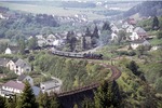 053 061 (50 3061) verlässt mit einem Sonderzug den Bahnhof Daun auf der Eifelquerbahn in Richtung Mayen. Am Zugschluß schiebt 038 382 (38 2383) nach. Vorne das Streckengleis von Wittlich. Über das Viadukt verläuft heute der Maare-Mosel-Radweg. (04.06.1972) <i>Foto: Peter Schiffer</i>