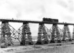 Eine 52 mit Kondenstender vom Bw Nikolajew führt die Belastungsprobe auf der abenteuerlich anmutenden Pfeilerbrücke über den südlichen Bug durch. Neben dem 300 m langen wiederhergestellten Kastenbrückenteil über den Fluss (vgl. Bild-Nrn. 18852 - 18856) führten die restlichen 700 m über diese Gerüstpfeilerbrücke an der Strecke Nikolajew (Mykolajiw) - Kolosowka. (1943) <i>Foto: RVM (Hollnagel)</i>