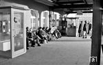Beim Warten auf den Zug genießen die Reisenden die Wintersonne in Dortmund Hbf. Dortmund besaß Anfang 1974 offenkundig noch eine Bahnsteigsperre, an der gerade heftige Diskussionen stattfinden. Obwohl bereits 1965 von der DB angekündigt, wurden die Bahnsteigsperren erst zur Weltmeisterschaft 1974 flächendeckend abgeschafft. (30.01.1974) <i>Foto: Johannes Glöckner</i>