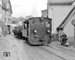 Eine der Hauptgründe für die Stillegung der Bahn war die Gleislage im Straßenplanum, auf dem auch die Rangierarbeiten zu den Werksanschlüssen stattfanden. Mit zunehmenden Straßenverkehr wurde sie somit zu einer großen Behinderung des Straßenverkehrs, wie hier die Lok 4 bei der Fahrt durch die Grünestraße bei “Klein-Landemert” in Plettenberg. (27.05.1961) <i>Foto: Detlev Luckmann</i>
