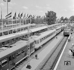 Blick auf das Ausstellungsgelände der IVA 1965, die vom 25. Juni bis 3. Oktober 1965 auf dem Messegelände Theresienhöhe in München stattfand. Auf dem Freigelände wurden auf neun Gleisen mit 3500 m Schienen mehr als 100 Schienenfahrzeuge ausgestellt, unter ihnen die gerade fertiggestellte E 03, aber auch andere Zugpferde wie E 10.12, E 50, V 169, V 200.1, V 320 und die Triebwagen ET 27, ETA 150, VT 11.5, VT 24.6, aber auch französische und belgische Loks wie die SNCF CC 40100 mit INOX-TEE-Wagen. Ein Schwerpunkt waren auch moderne Güterwagen verschiedenster Bauarten. Zur IVA kamen 3,2 Millionen Besucher. (07.1965) <i>Foto: Dieter Kempf</i>