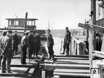Nachfolgende Bildserie entstand im Frühjahr 1943 an der Anlegestelle Cherson Fähre und dokumentiert den Arbeitsalltag am Fährhafen. Das nächste Fährboot wird für die Beladung vorbereitet, dabei ist ein entspannter Plausch zwischen Eisenbahnern und Wehrmachtsangehörigen natürlich selbstverständlich. Im Hintergrund wartet ein zuvor beladenes Fährschiff auf den Abtransport nach Aljeschki Fähre. (1943) <i>Foto: RVM (Hollnagel)</i>