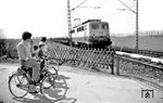 140 754 (Bw Oberhausen-Osterfeld Süd) passiert mit einem Güterzug eine fahrradfahrende Familie an einem Bahnübergang bei Horn zwischen Bad Sassendorf und Lippstadt. (13.04.1980) <i>Foto: Johannes Glöckner</i>
