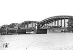 Eine unbekannte 03 fährt über die Süderelbebrücke zwischen Hamburg-Wilhelmsburg und -Harburg. Die Eisenbahn überquert seit 1872 hier die Süderelbe mit einer Bogenbrücke. Wie an der Norderelbe wurde diese Brücke vom Brückenbauunternehmen Harkort errichtet. Im Rahmen der von 1970 bis 1979 durchgeführten Erneuerung der Süderelbbrücke wurde die alte Brücke abgerissen.  (1955) <i>Foto: Walter Hollnagel</i>
