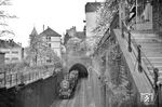 Man muss schon genau hinsehen, aber hier verlässt tatsächlich eine Doppeltraktion mit 38 1869 und 38 3395 vor P 2365 das Westportal des Schloßbergtunnels. Kurioses am Rande: Links neben diesem Einschnitt verläuft sichtbar der „Obere faule Pelz“, daneben der hier nicht sichtbar der „Untere faule Pelz“ mit dem Stadtgefängnis. In den Straßen mit dem besagten "faulen Pelz" (die es im übrigen nur in Heidelberg gibt) lebten keine Faulpelze - es war auch kein Spitzname für die dort einsitzenden Gefängnisinsasssen - sondern hier wirkten eigentlich fleißige Handwerker, nämlich Gerber. Nach deren Wegzug im 17. Jahrhundert wurde dem Graben, aus dem die Gerber das Wasser entnahmen, kein Frischwasser mehr zugeführt. In der Folge begann es an zu faulen und bildete schließlich ein dicke Schimmelschicht - den "Pelz". Das Gelände unterhalb des Grabens hieß von nun an "Untere faule Pelz", das darüber der "Obere faule Pelz". Obwohl der Graben längst zugschüttet ist, blieb der Name erhalten. (30.04.1955) <i>Foto: Helmut Röth *</i>