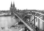 Blick aus dem rechten Deutzer Brückenturm auf die behelfsmäßig zweigleisig wiederhergestellte Hohenzollernbrücke, die gerade von einem Personenzug mit einer pr. P 8 (Baureihe 38.10) befahren wird. Über der mittleren Stromöffnung liegt ein SKR-Stahlüberbau (Schaper-Krupp-Reichsbahn), der 1952 wieder durch einen Bogen ersetzt wurde. (1948) <i>Foto: Fischer</i>