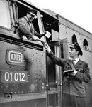 Der Lokführer der 01 012 erhält in Hannover Hbf die Zugpapiere (Wagenliste und Bremszettel) vom Zugführer. Sie sind Voraussetzung für eine sichere Zugfahrt, erhalten sie doch u.a. die individuellen Daten über Gewicht, zulässige Höchstgeschwindigkeit und Bremsvermögen des Zuges.  (1959) <i>Foto: H. Brunotte</i>