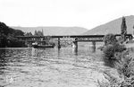 Seit dem Krieg konnte die Brücke über den Neckar bei Neckargemünd als Notbrücke nur eingleisig und mit Schrittgeschwindigkeit befahren werden (vgl. auch Bild-Nrn. 47365, 47790, 47791). Für den eingleisigen Betrieb wurde auf der Kleingemünder Seite extra die "Abzw Kleingemünd" eingerichtet. Die Brücke wurde endlich 1958 erneuert. (14.09.1958) <i>Foto: Helmut Röth *</i>