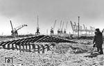 Wie stählerne Skelette überragen die Hafenkräne am Diestelkai die Reste der Gleisanlagen. Bemerkenswert ist, dass offenbar keiner der Kräne durch die Druckwellen der Bombeneinschläge von den Kranschienen gehoben oder gar ins Hafenbecken gekippt wurde.  (29.07.1944) <i>Foto: Walter Hollnagel</i>