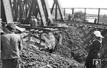Die Beseitigung der Schäden an diesem Bombenkrater in Veddel dauerte wohl etwas länger. Einer der wenigen Bilder, wo im Hintergrund ein Bewacher zu sehen ist, dem wohl gerade - im Gegensatz zu den Arbeitern - das Mittagessen gebracht wird.  (08.1944) <i>Foto: Walter Hollnagel</i>