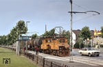 Lok 14 (AEG 1913) und Lok 15 (AEG 1928) der Bahnen der Stadt Monheim befördern einen Güterzug an der Rheinpromenade in Monheim. Die aktuellen Spritpreise an der Shell-Tankstelle (rechts) betragen 95,9 Pfennig für Normalbenzin und 1,01 DM für Super. (18.07.1979) <i>Foto: Peter Schiffer</i>