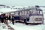 Der Postbusverkehr von Ochsenhausen nach Biberach traf im Winter 1971/72 auf unerwartete Schwierigkeiten. Ein Bus blieb auf einer Steigung hängen. Die Fahrgäste nahmen es gelassen, für die Dorfjugend war es eine Gaudi. Bei dem vorderen (privaten) Reisebus - er fährt "im Auftrag der Deutschen Bundespost"- handelt es sich um einen "Neoplan" Typ NH 10/11, gebaut ca. 1960 vom Bushersteller Gottlob Auwärter aus Stuttgart. (1972) <i>Foto: Dieter Junker</i>