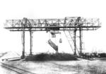 Kipperkatzenverladebrücke der Fa. Demag im Hafen von Wilhelmshaven. In der Originalbeschreibung heißt es: "Zum Zweck der raschen Entladung von Kohlenwaggons wurde die maschinelle Ladeeinrichtung gebaut. Der Brückenkran hebt die Waggons gleichmäßig an und dreht sie zu der Entladestelle. Die Brücke besitzt eine Stützweite von 40 m und eine lichte Höhe von 22 m. Die Kipperkatze ist für eine Nutzlast von 40 t eingerichtet und kann mittels der Kipperplattform 15 Wagen/Std entleeren. Um die Verwendungsfähigkeit der Brücke zu erhöhen und das Verladegut dem Lager entnehmen zu können, ist die Katze mit einem Auslegerarm von 7 m versehen und ein Greiferwindwerk von 20 t Tragkraft eingebaut, wodurch bei Greiferbetrieb eine stündliche Leistung von 150 t erzielt wird." (1930) <i>Foto: RVM</i>