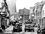 Nachdem die Alliierten Truppen im Frühjahr 1945 das linke Rheinufer bis Koblenz erobert hatten und die Brücke von Remagen unzerstört einnehmen konnten, kämpften sie sich entlang des Rheins in nördlicher und südlicher Richtung vor und gelangten am Palmsonntag, dem 25. März 1945, bis nach Engers und Bendorf. Der direkte Weg über den Rhein war seit der Sprengung der "Kronprinz-Wilhelm-Brücke" bei Engers durch deutsche Truppen am 9. März 1945 verwehrt. Die Besetzung der Stadt Engers durch die 1. US-Armee scheint halbwegs friedlich abgelaufen zu sein, da weiße Fahnen gehisst wurden. (27.03.1945) <i>Foto: Pressefoto ACME</i>
