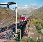 Zug 130 von Brig nach Zermatt auf der Steffenbachbrücke der Furka-Bergstrecke zwischen Realp und Tiefenbach. Die 1925 gebaute stählerne Brücke hat eine Spannweite von etwa 36 Metern und eine grösste Höhe von etwa 17 Metern. Sie ist bemerkenswert, weil sie jeden Herbst ab- und im Frühjahr wieder aufgebaut werden muss, um sie vor Lawinen zu schützen.  (1981) <i>Foto: Karsten Risch</i>