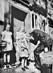 Stationsvorsteher Edith sichert den Kriegsverkehr: "Der Dienst ist zu Ende. Mutti, die tüchtige Aufsichtsbeamtin, kann sich nun Ihrem Heim und Ihren Kindern widmen. Jedesmal ist die Freude gross, wenn sie wieder daheim ist." (1942) <i>Foto: Atlantic/Ahrweiler</i>