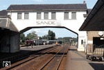 Der Bahnhof Sande an der Strecke Wilhelmshaven - Oldenburg mit seinem prägnanten Bahnsteigzugang. Im Hintergrund fährt 211 094 ein. (01.09.1980) <i>Foto: Peter Schiffer</i>
