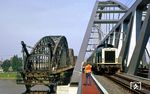 Während die Abrissarbeiten an der alten Hammer Rheinbrücke in vollem Gange sind, passiert 212 238 mit N 8174 nach Neuss die Baustelle über die neue Rheinbrücke. (04.07.1987) <i>Foto: Wolfgang Bügel</i>