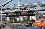 Auf der Bundesallee (Bundesstraße 7) in Elberfeld traf die Straßenbahn auf ein anderes Wuppertaler Wahrzeichen, die Schwebebahn, hier repräsentiert durch das Einzelstück Wagen 101, der 1962 als erster Gelenktriebwagen aus den Wagen 65 und 66 umgebaut worden war und, um den Effekt herauszustellen, blau lackiert wurde. (10.04.1974) <i>Foto: Dieter Junker</i>