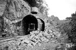 V 100 1327 am Lichtensteiner Kopf-Tunnel (92 m) bei Neidenfels. Der Tunnel musste für die Elektrifizierung aufgeweitet werden. Dies verzögerte die Fertigstellung des elektrischen Betriebs auf der Strecke nach Kaiserlautern, der schließlich ab dem 12. März 1964 auf gesamter Länge aufgenommen werden konnte. Man hatte zunächst wegen der Kürze des Tunnels und der Beschaffenheit des Gesteins erwägt, diesen aufzugeben und die Bergnase zu umfahren. Dies hätte aber einer späteren Erhöhung der Streckengeschwindigkeit im Wege entstanden. (25.06.1963) <i>Foto: BD Mainz, Slg. W. Löckel</i>