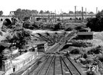 Das in unmittelbarer Nähe zum Bw Köln-Betriebsbahnhof (im Hintergrund) gelegene Bw Köln-Gereon führte eher ein Schattendasein. Es lag im tieferliegenden Dreieck der Zufahrtsgleise aus Köln-Süd, -Nippes und -Ehrenfeld. Der ursprünglich vorhandene Ringlokschuppen wurde im Zweiten Weltkrieg zerstört. Auf den verbliebenen Freiständen wurden noch bis in die 1960er Jahren Dampfloks für den Einsatz im nahen Eilgutbahnhofs Gereon abgestellt. Der Schnellzug im Hintergrund fährt von Köln Hbf kommend um das Gelände des Bbf herum in Richtung Köln-West auf die linke Rheinstrecke. Die E 10 wird gleich die Streckengleise aus Köln-Nippes bzw. -Ehrenfeld überqueren. (1966) <i>Foto: Fischer</i>