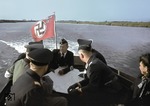 Albert Ganzenmüller (Bildmitte mit Karte) mit seinem Stab und Sekretärin unterwegs auf dem Dnjepr bei Cherson zu der im Bau befindlichen Eisenbahnbrücke über das Dnjepr-Delta. (07.1943) <i>Foto: Walter Hollnagel</i>