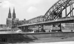 Nachdem am 6. März 1945 die Brückenpfeiler der Hohenzollernbrücke in Köln durch Pioniere der sich zurückziehenden Deutschen Wehrmacht gesprengt wurden, konnte ab 1948 wieder ein provisorischer zweigleisiger Betrieb über die Brücke aufgenommen werden. Als Ersatz für die zerstörte Straßenbrücke wurde lediglich ein Geh- und Radweg angesetzt. Auf der Brücke begegnen sich eine 50 ÜK (rechts) und eine aus dem Hauptbahnhof ausfahrende 01. (1950) <i>Foto: Fischer</i>