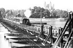 Parallel zur Maxauer Rheinbrücke existierte im Zuge der "Pfälzischen Ludwigsbahn" (Heidelberg–Schwetzingen–Speyer) eine weitere Schwimmbrücke von 1866 bis 1938 über den Rhein. Auf der 5,90 m breiten Brücke mussten sich der Individualverkehr und die Eisenbahn den Platz teilen. Die Schienen waren bündig in die Fahrbahn eingelassen. Die Gesamtlänge der Brücke betrug 402 m. Unter der Konstruktion ruhten 43 Kähne in einem Abstand von jeweils 2,48 m. Wenn ein Schiff passieren wollte, wurde die Brücke an der betreffenden Stelle getrennt. Am 20. Januar 1938 wurde die Schiffsbrücke durch eine feste Konstruktion ersetzt. Diese wurde allerdings auch nur 8 Jahre alt, weil deutsche Truppen sie kurz vor Kriegsende sprengten. Hier überquert die bayr. D VI (98 7502) mit einem Personenwagen die schwankende Rheinbrücke.  (1930) <i>Foto: RVM</i>