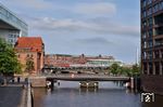 Blick auf die Ericusbrücke (vorne) und die Oberhafenbrücke, auf der gerade eine 218 den IC 2415 aus Fehmarn-Burg zum Hamburger Hauptbahnhof bringt. (21.08.2021) <i>Foto: Zeno Pillmann</i>
