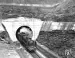 39 009 (Bw Karlsruhe) am neuen Bildstock-Tunnel im saarländischen Friedrichsthal an der Saarbrücken – Türkismühle. Der starke Kohleabbau in der Region führte von Anfang an zu großen Problemen an der Bahnstrecke, da Bergschäden zu häufigen Instandsetzungsarbeiten führten. Immer wieder gab es Überlegungen, die Bahnstrecke zu verlegen und auch den Bildstock-Tunnel abzureißen und durch einen Einschnitt zu ersetzen. Ab 1946 wurden die Grubenschäden immer stärker. Außerdem entdeckte man unter dem Bildstock-Tunnel große Kohlevorkommen, die man bei einer Anhebung und Belassung der alten Strecke nicht hätte fördern können. Ein Aufschlitzen des Tunnels hätte einen rund 60 Meter tiefen Einschnitt hinterlassen, der das Dorf Bildstock geteilt hätte. Die Saarbergwerke und Eisenbahndirektion Saarbrücken beschlossen deshalb den Neubau eines Tunnels. Der neue 336,8 m Bildstocktunnel entstand rund 150 Meter westlich des alten Tunnels. Am 3. Juli 1955 durchfuhr der erste Zug den neuen Tunnel. Der alte Tunnel wurde verfüllt, die Eingangsportale aus Sandstein zugeschüttet. (1955) <i>Foto: RBD Saarbrücken</i>